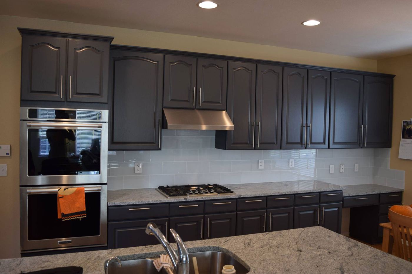 Kitchen cabinets painted dark charcoal with granite counters and double wall ovens