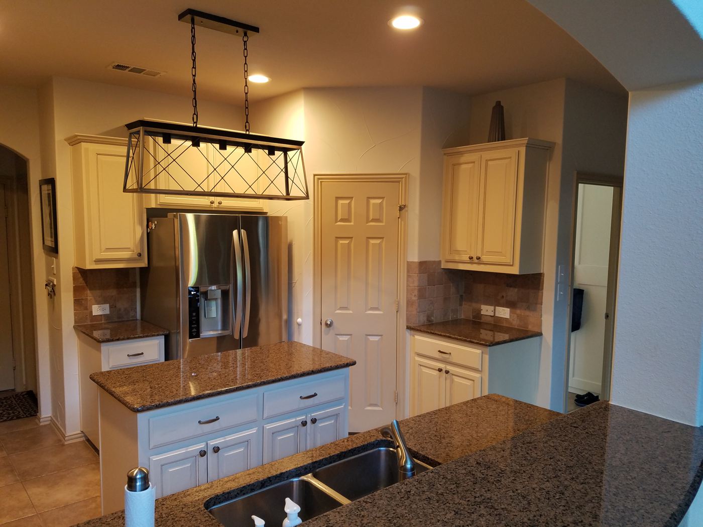 Cream painted cabinets and island under a black linear chandelier