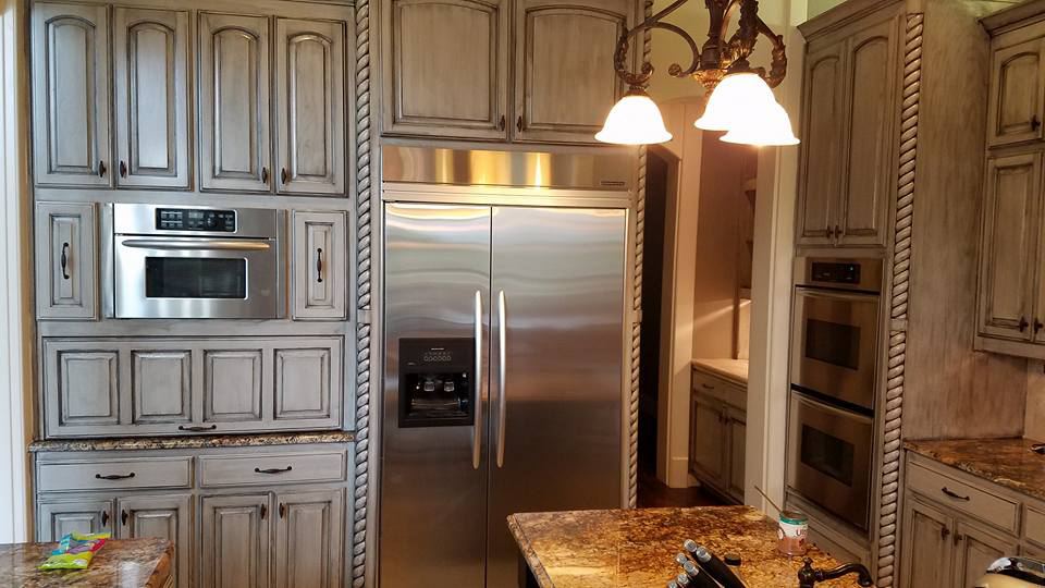 Cabinets finished in a gray glaze around a built-in refrigerator