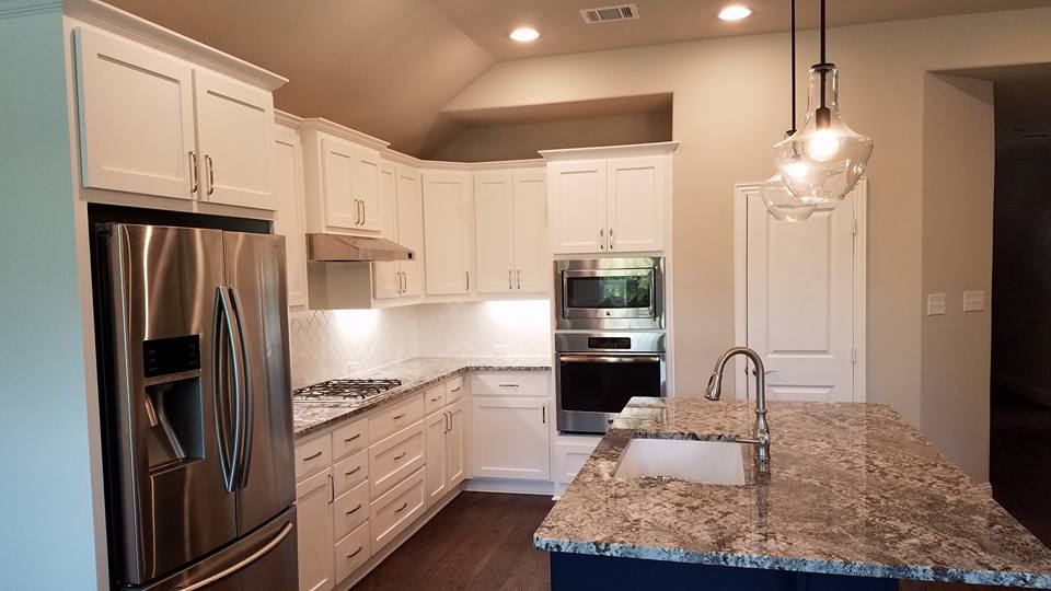 White painted cabinets, a granite island and a stainless refrigerator