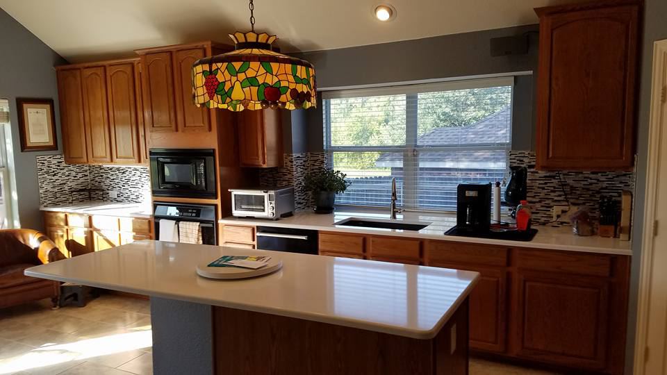 Orange-toned oak cabinets under a stained-glass pendant, before painting