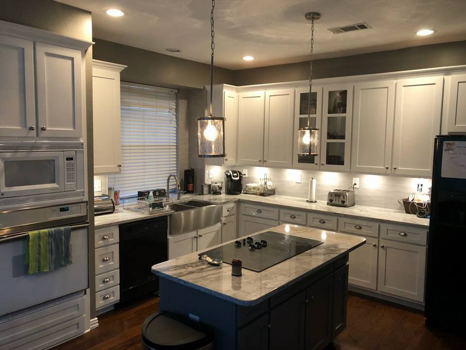 White painted cabinets with a blue-gray island and two pendants