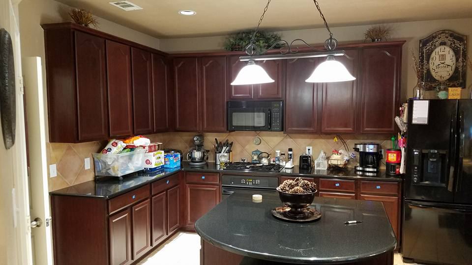 Cherry-stained kitchen cabinets with a round black granite island, before