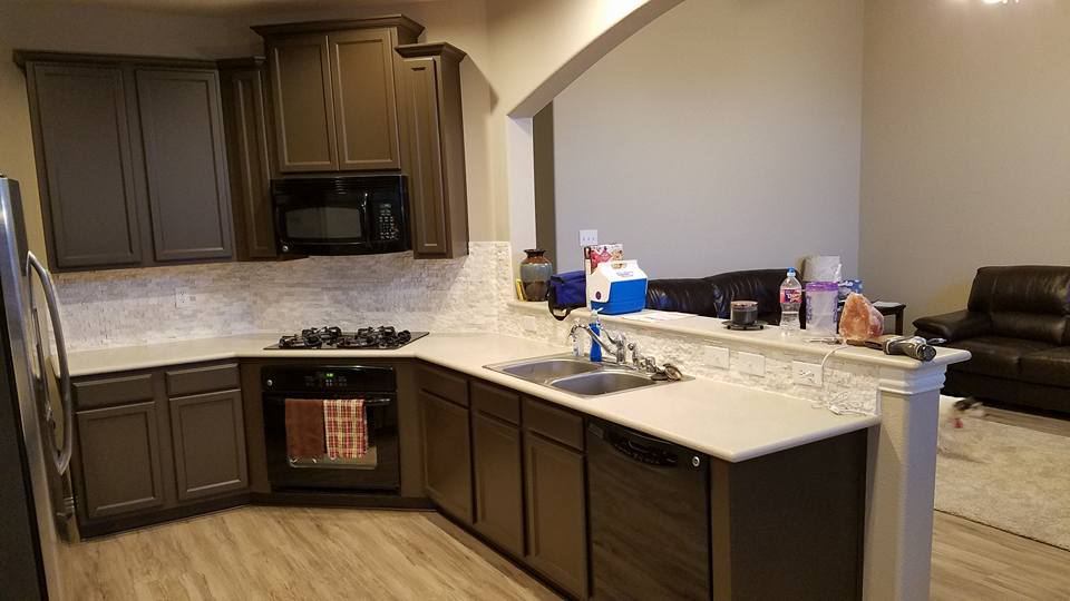 Kitchen cabinets painted dark brown with light quartz counters