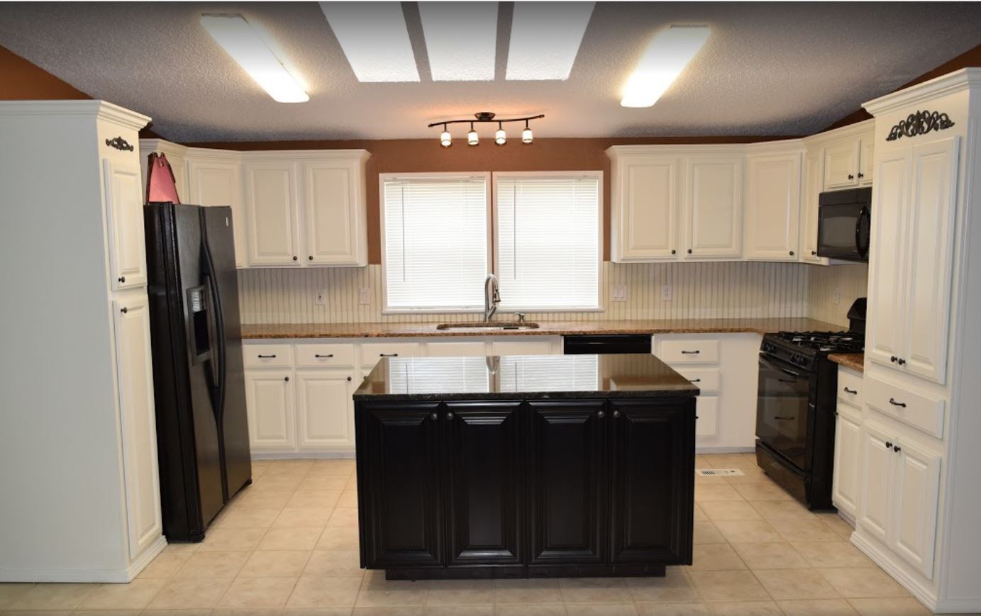 Cream painted cabinets with a black island under a skylight